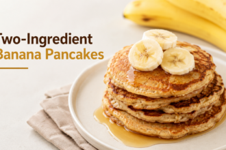 A stack of golden-brown, thin banana pancakes plated on a ceramic dish, topped with fresh strawberries and a side of Greek yogurt.