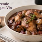 A portion of quick coq au vin served in a Dutch oven, featuring golden-brown chicken thighs, mushrooms, and carrots in a rich wine reduction.